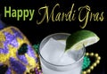 Alcoholic beverage and pourple, green and gold Mardi Gras beads with mask on a black bckground for a festive February holiday imag