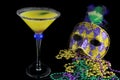 Alcoholic beverage and pourple, green and gold Mardi Gras beads with mask on a black bckground for a festive February holoiday ima