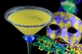 Alcoholic beverage and pourple, green and gold Mardi Gras beads with mask on a black bckground for a festive February holiday Royalty Free Stock Photo