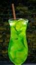 Alcoholic cocktail in a glass on a brick wall background. Vertical image Green lemonade with ice. Summer fresh drink Royalty Free Stock Photo