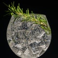alcoholic cocktail with ice and rosemary on a black background,