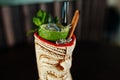 Alcoholic cocktail with mint and lime with fire in originally voodoo earthen glass on bar table. Royalty Free Stock Photo