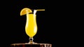 Alcoholic cocktail with a straw on a black background. Yellow lemonade in a glass on a wooden board. Fruit drink Royalty Free Stock Photo