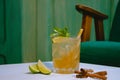 Alcoholic coctail with mint and powdered sugar in the form of decoration with lime and cinnamon lying next to it