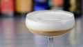 Alcoholic coffee cocktail with a nutty note and fluffy milk foam on the background of the bottles at the bar
