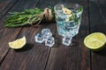 Alcoholic drink - gin tonic cocktail - with lime, rosemary and ice on rustic wooden table Royalty Free Stock Photo