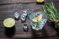 Alcoholic drink - gin tonic cocktail - with lime, rosemary and ice on rustic wooden table Royalty Free Stock Photo