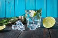 Alcoholic drink - gin tonic cocktail - with lime, rosemary and ice on rustic wooden table Royalty Free Stock Photo