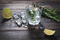 Alcoholic drink - gin tonic cocktail - with lime, rosemary and ice on rustic wooden table Royalty Free Stock Photo