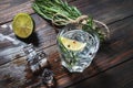 Alcoholic drink - gin tonic cocktail - with lime, rosemary and ice on rustic wooden table Royalty Free Stock Photo