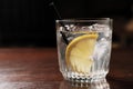 Alcoholic drink with lemon and ice on a old wooden table