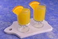 Alcoholic drink with orange juice in small glasses on a blue background. Royalty Free Stock Photo