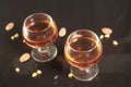 Two cognac glasses on black background with almonds.