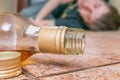 Alcoholic drunk man is sleeping on floor. Bottle with whiskey in front