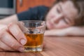 Alcoholic woman is sleeping on table. Glass with alcohol in hand