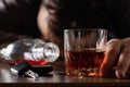 Alcoholism, alcohol addiction and people concept - male alcoholic with glass of whiskey lying or sleeping on table. Keys from auto Royalty Free Stock Photo