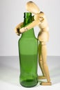 Alcoholism, alcohol addiction, social problem: a wooden dummy, a lonely drunkard, an alcoholic, hugging a bottle of beer