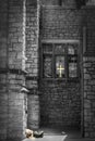 Alcove outside church with golden cross in window and homeless man asleep - only party visible with head in sunshine B&W