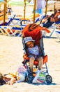 Alcudia, Spain 14.09.2011 - Child covered in sand in stroller on sandy beach sleeping. Kids at summer vacation in sun concept