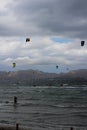 Kitesurfers ride the waves on the beach of Playa de Alcudia against a gray overcast sky . Alcudia. Royalty Free Stock Photo