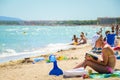 Alcudia, Spain 14.09.2011 - Young woman reading a book at sandy beach. People sunbathing at Playa de Muro. Mallorca island famous