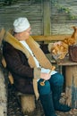Male doctor veterinarian sits at a table outdoor and strokes a ginger cat on the back. Royalty Free Stock Photo