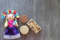 Alegrias y palanquetas, mexican amaranth and seed candies with mexican craft doll on vintage wooden gray background