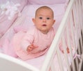 Alert curious little baby girl in a cot.