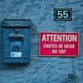 Rusty french mail box and sign warning for snow Royalty Free Stock Photo