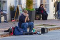 A white bearded elderly street musician playing harmonica