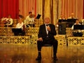 Alexandru Arsinel sitting on a chair and singing on the stage of the Theater Constantin Tanase