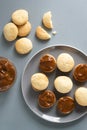 Alfahores cookies on a gray plate on a gray background with condensed milk in a glass bowl. Royalty Free Stock Photo