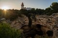 Alfanzina Lighthouse, as seen framed by trees, sunflare and sea caves at sunset in the Algarve region of Portugal Royalty Free Stock Photo