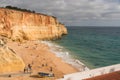 Golden cliffs tower over a sandy beach with scattered visitors in Algarve, Portugal Royalty Free Stock Photo