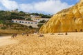 Visitors enjoy a day at the beach beneath the cliffside homes of Algarve