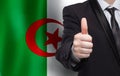 Algerian concept. Businessman showing thumb up on the background of flag of Algeria Royalty Free Stock Photo