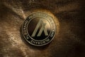 Algorand ALGO Crypto Coin Placed on brown fabric and partially lit with natural light