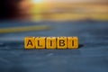 Alibi on wooden blocks. Cross processed image with bokeh background Royalty Free Stock Photo