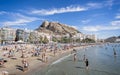 Alicante beach packed with sun bathers, and Santa Barbara castle in Alicante, Spain