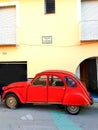 Red Citroen CV2 small car parked outside yellow building