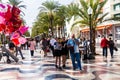 Alicante, Spain- November 04, 2018- Teenage girls and men eat roasted chestnuts and people walk in the palm trees alley - the main Royalty Free Stock Photo