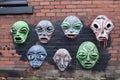 alien faces, with their eyes and mouths cut out, spray-painted on a brick wall