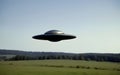 Alien UFO flying over a field. Royalty Free Stock Photo