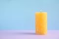 Alight wax candle on color background. Space for