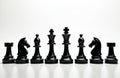 Aligned black chess set pieces showcase strategy game elements. Row of figures on white table represent strategic planning in Royalty Free Stock Photo