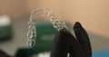 Aligners in the hands of the doctor, rubber gloves hold modern tools