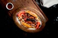 Alinazik kebab is a dish of grilled eggplant and lamb in a bun on a copper plate. Black background