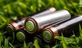 Alkaline aa size batteries on the green grass. Close up. Energy saving concept. Generative AI Royalty Free Stock Photo