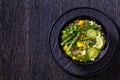 Alkaline green soup in black bowl, top view