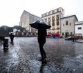 Man is walking with umbrella during heavy rain in the town